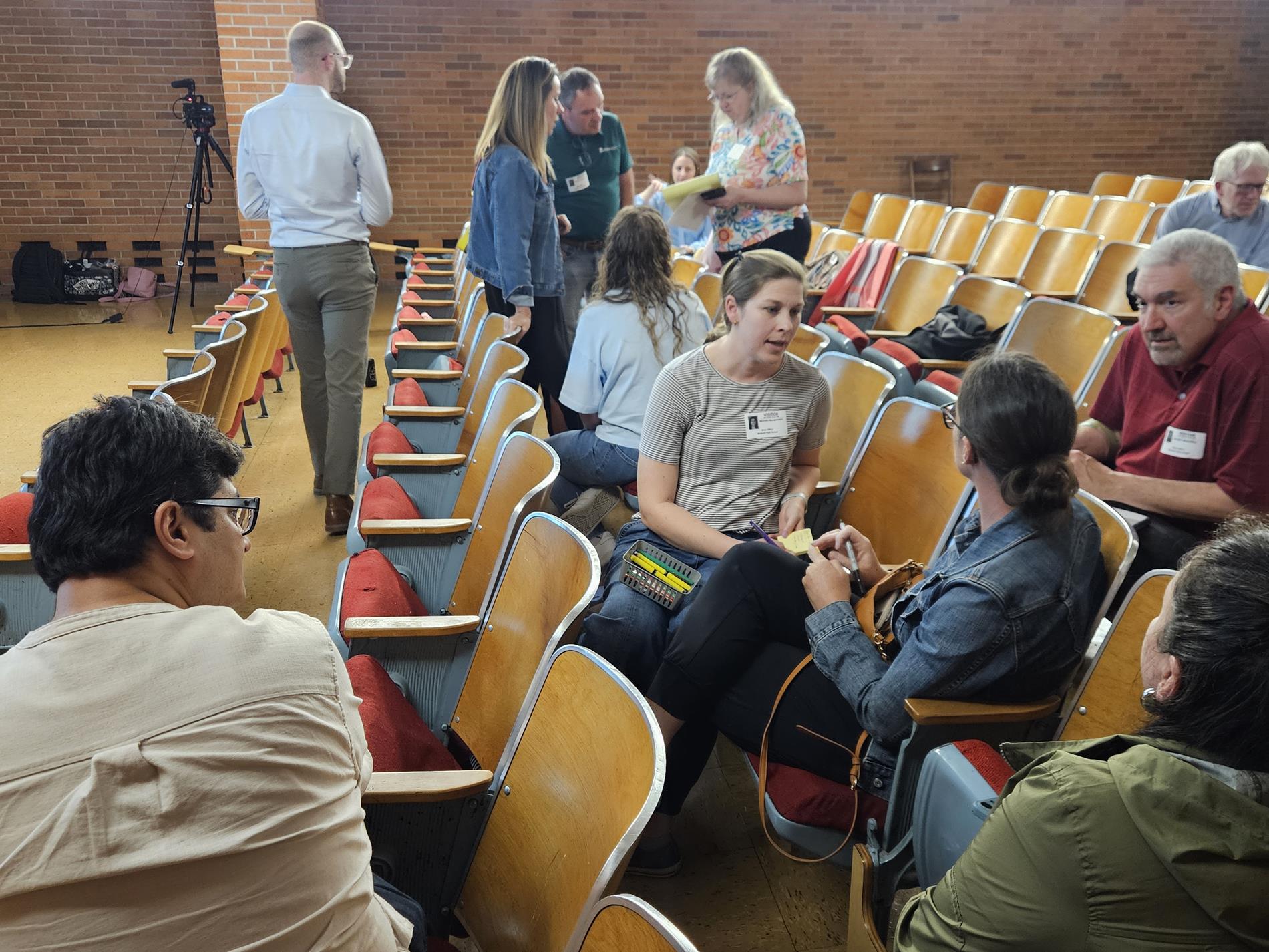 A group of community members sit in the Little Theater having a conversation about the facility planning presentation