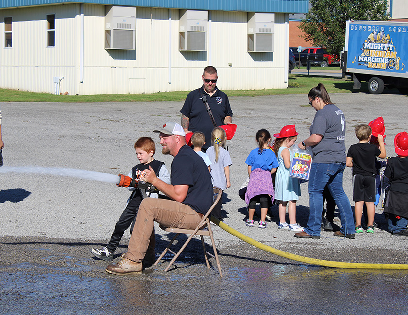 Fire Fighter Andrew Russell helps students with the fire hose