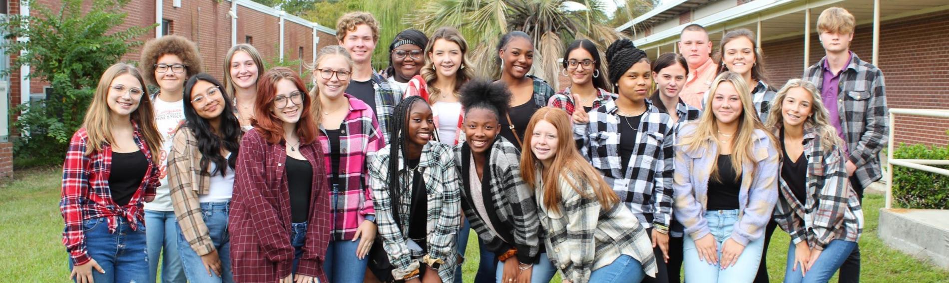 A large group of students pose together in flannel shirts on Flannel Day