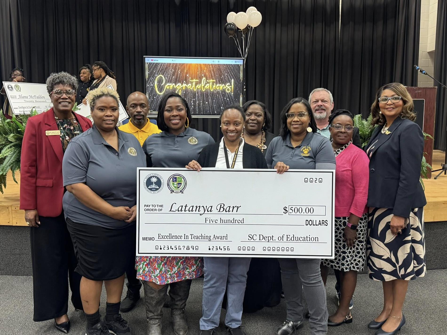 people standing holding large check 
