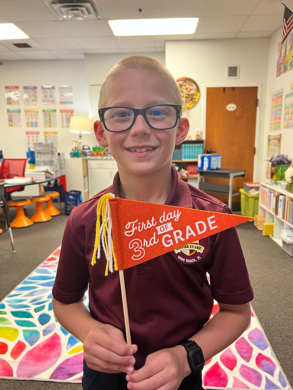 Lower school student holding "first day of 3rd grade" flag Lower school student holding "first day of 3rd grade" flag