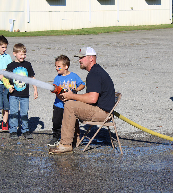 Fire Fighter Andrew Russell helps students with the fire hose