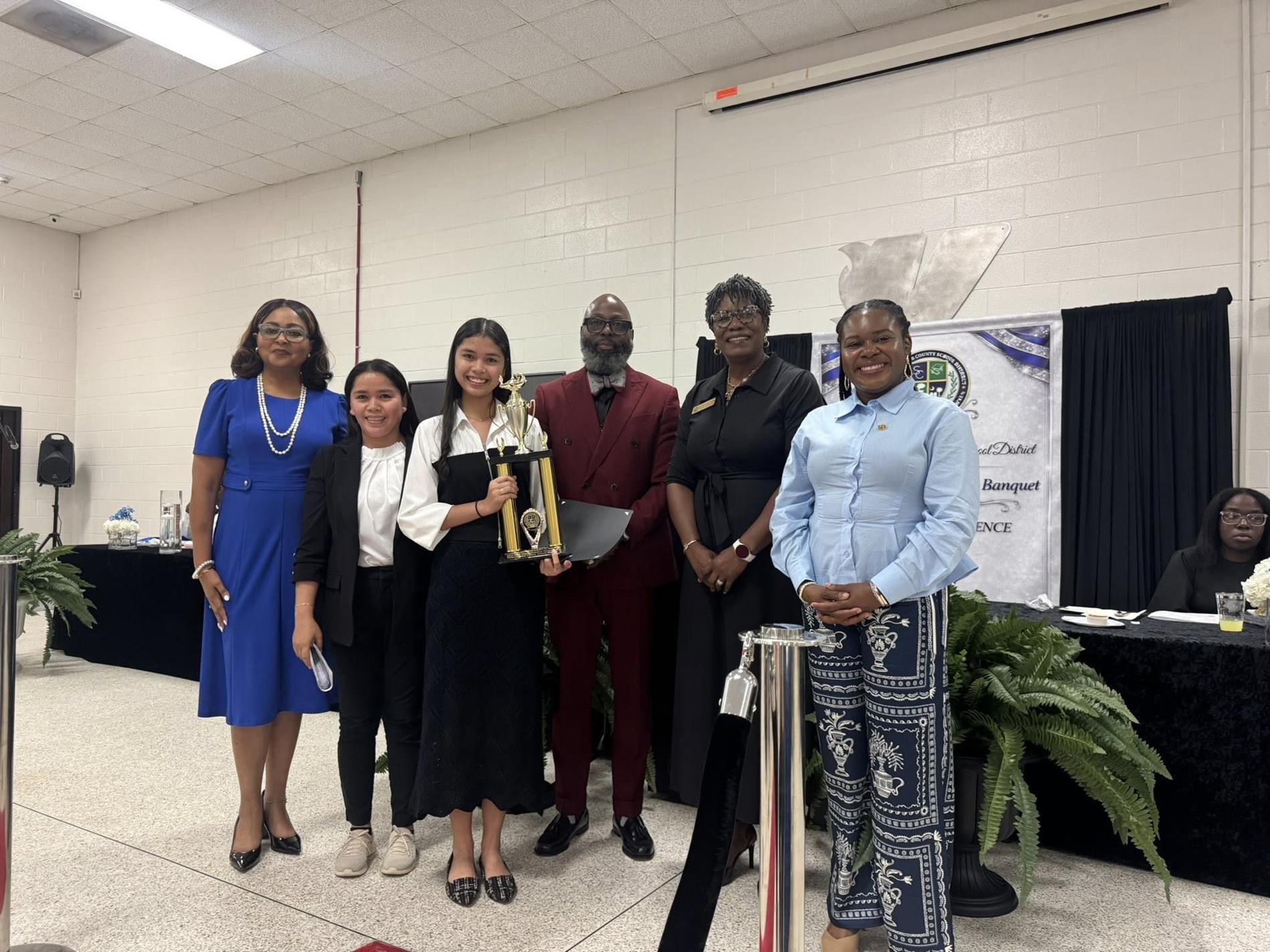 people standing together. one is receiving an award 