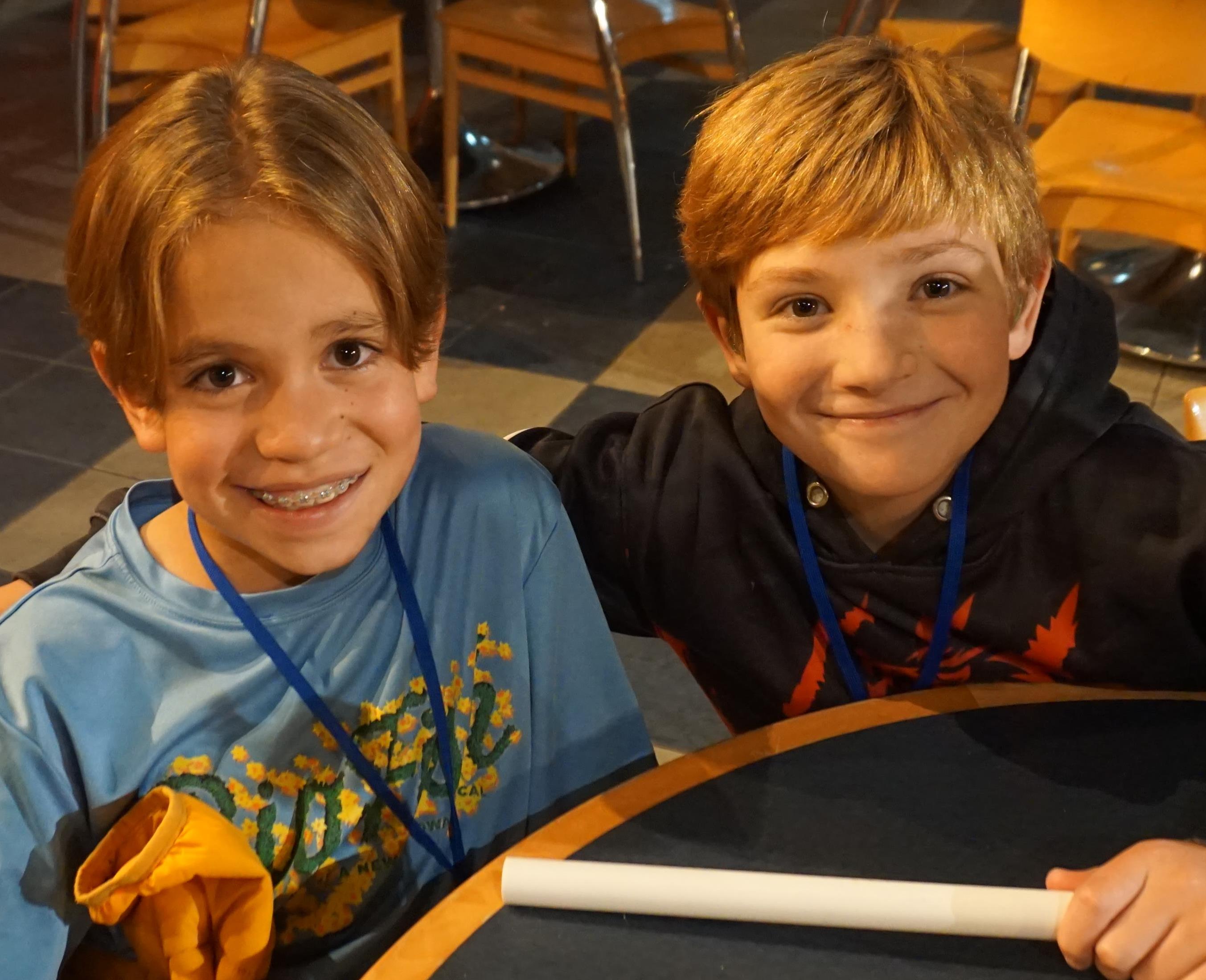 Two boys sitting at a table smiling
