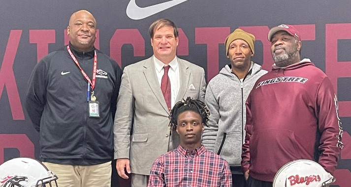 student athlete with coaches at college signing day