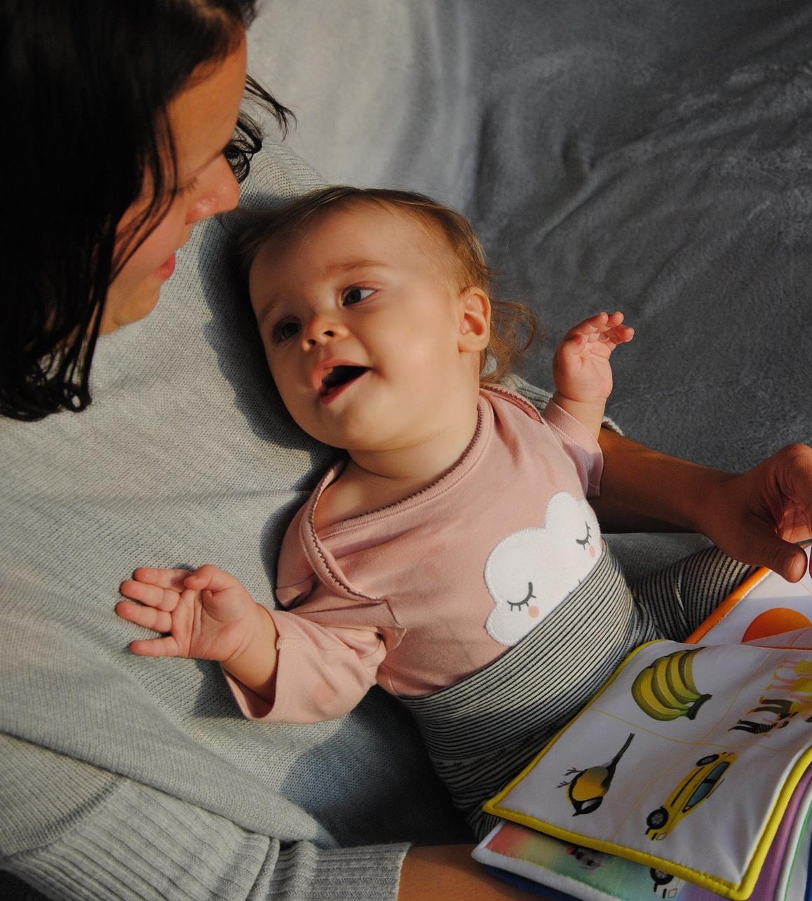 infant on parent lap smiling with open book