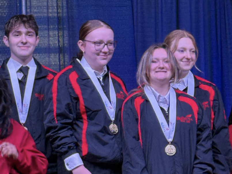 four students standing on top of a medal podium