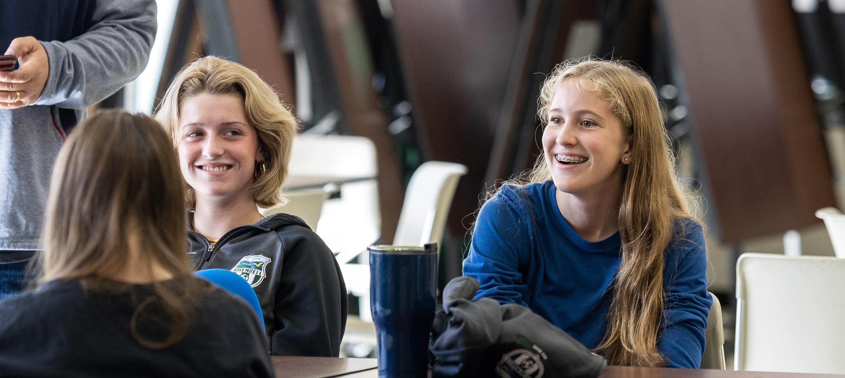 Students are laughing at talking during lunchtime in the cafeteria