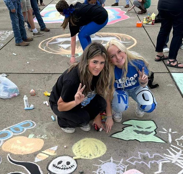 students draw halloween picture on the sidewalk with chalk