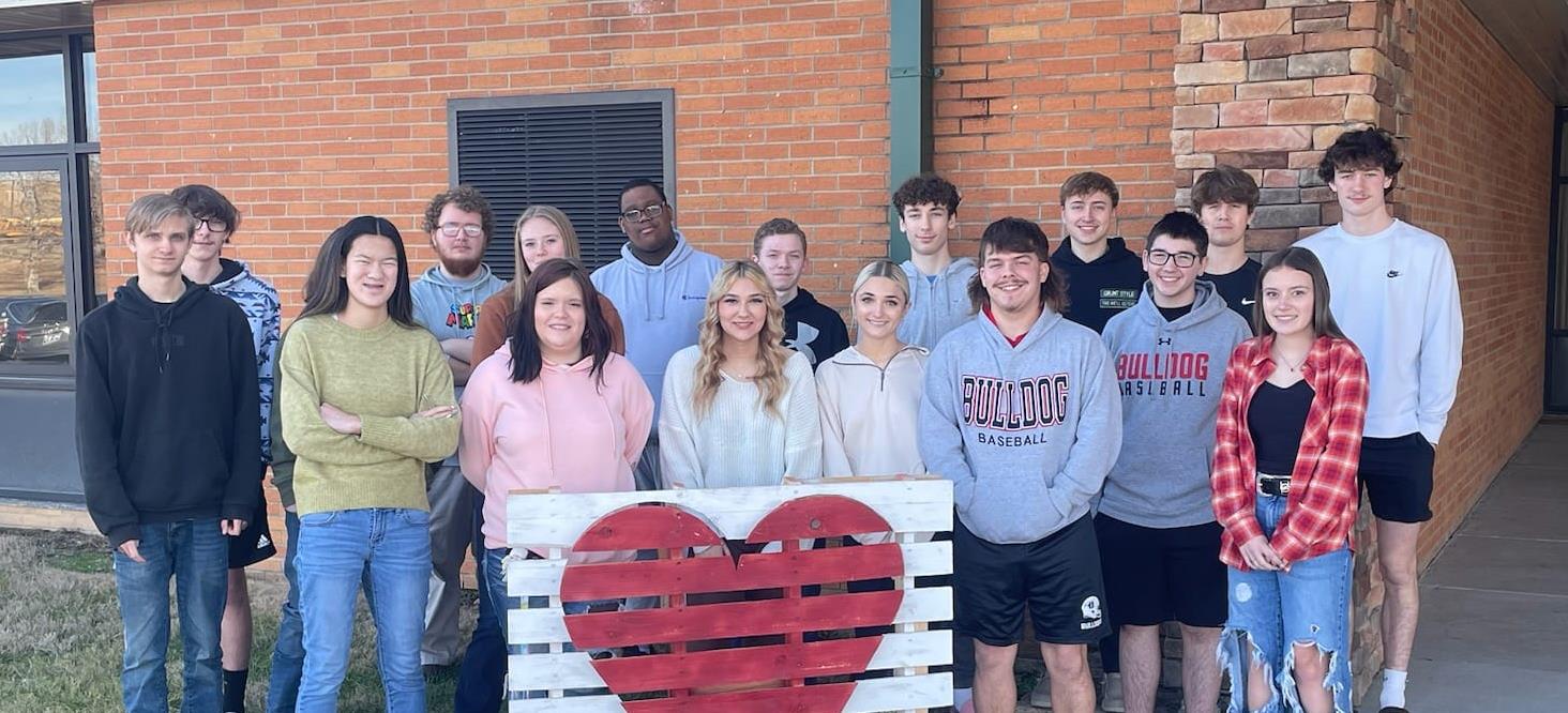 Class posing with a pallet painted with a heart