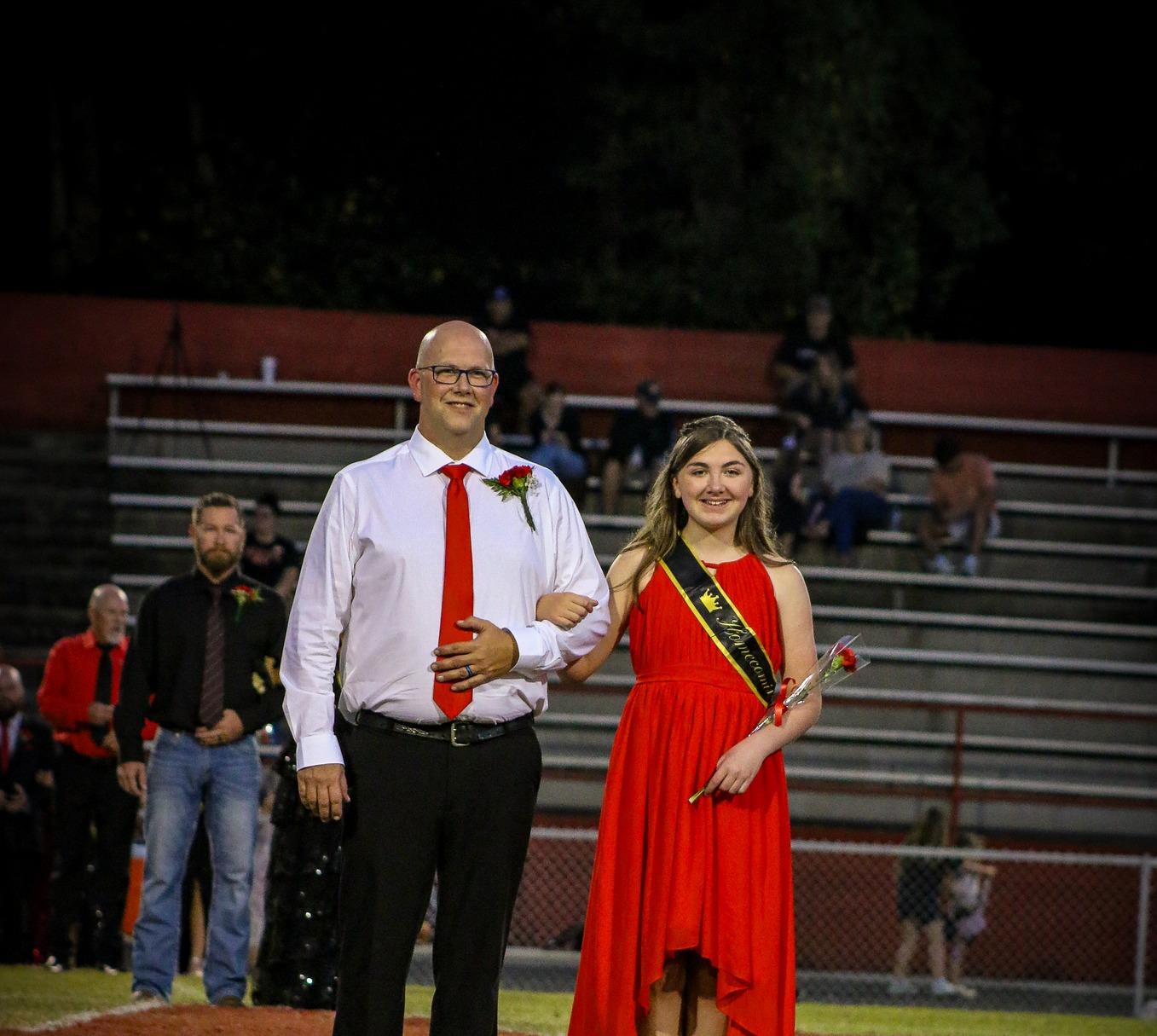 Homecoming attendant in a red dress with escort