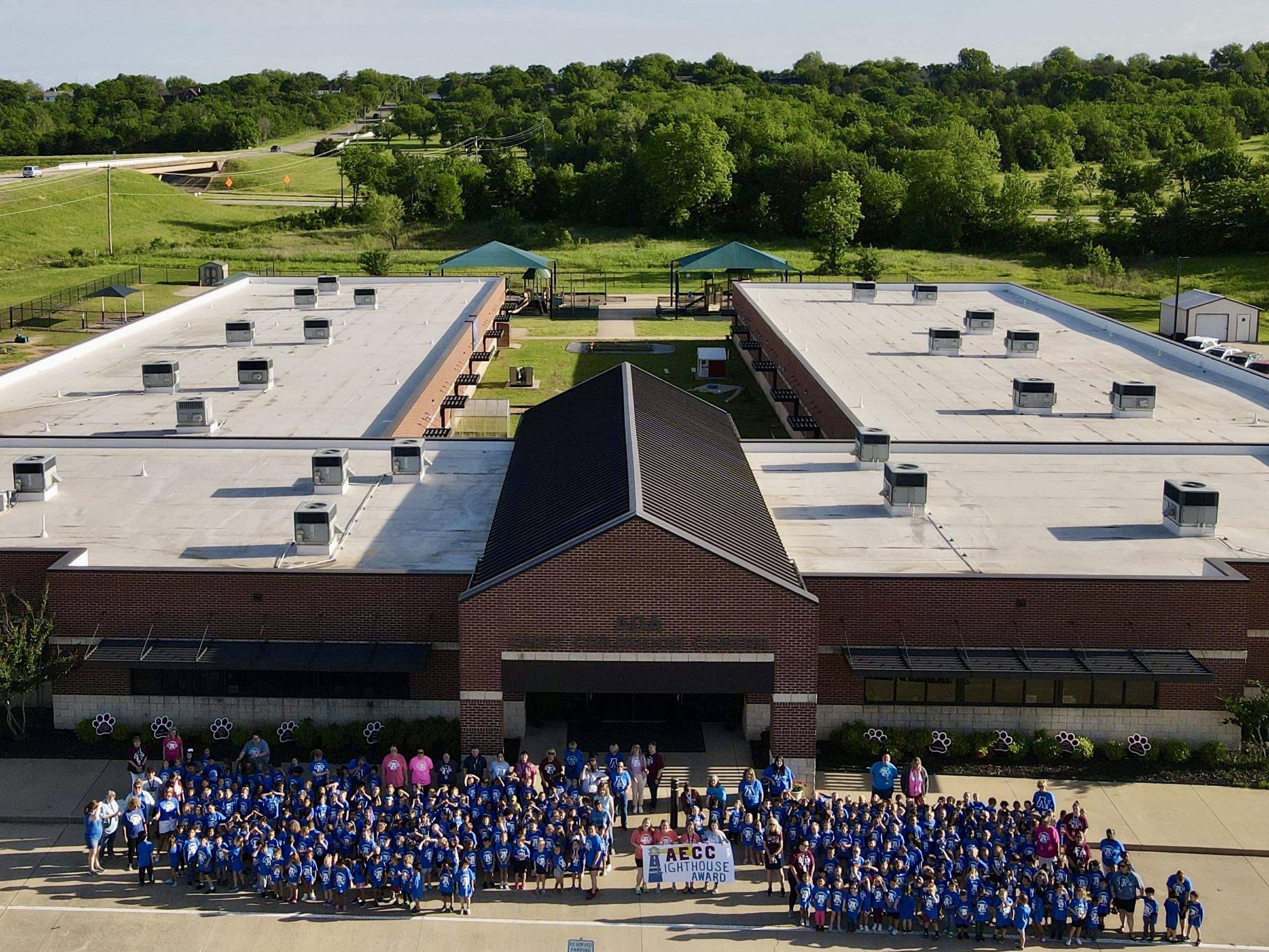 Students and faculty pose outside the Ada Early Childhood Center, celebrating the new status as a Leader in Me Lighthouse School.