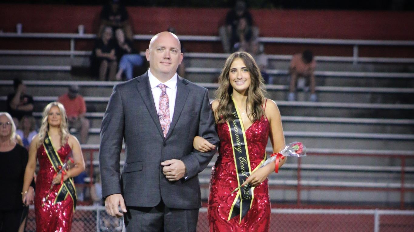 Homecoming attendant in a red dress with escort