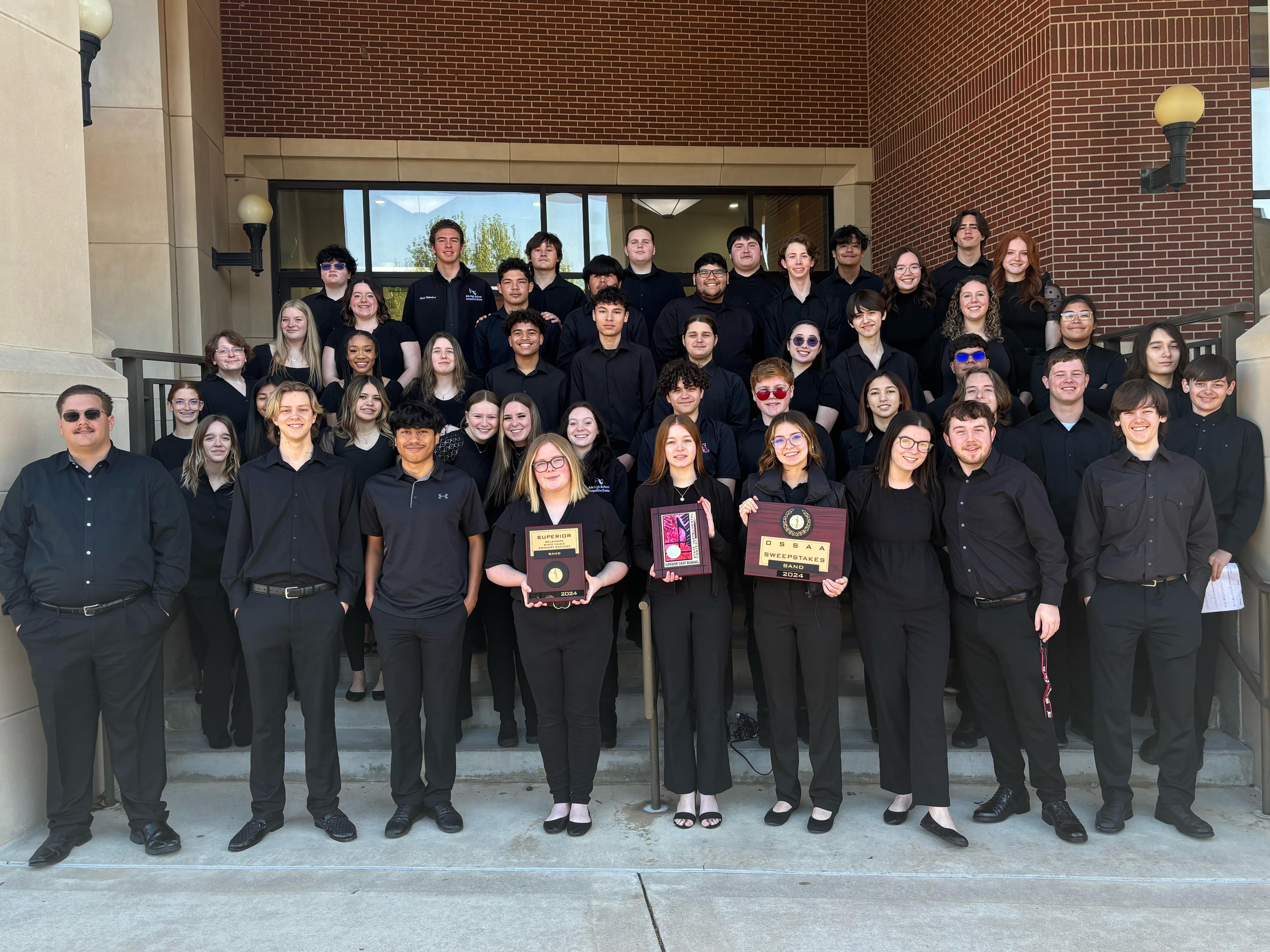 Ada High School Concert band poses for a picture holding awards.