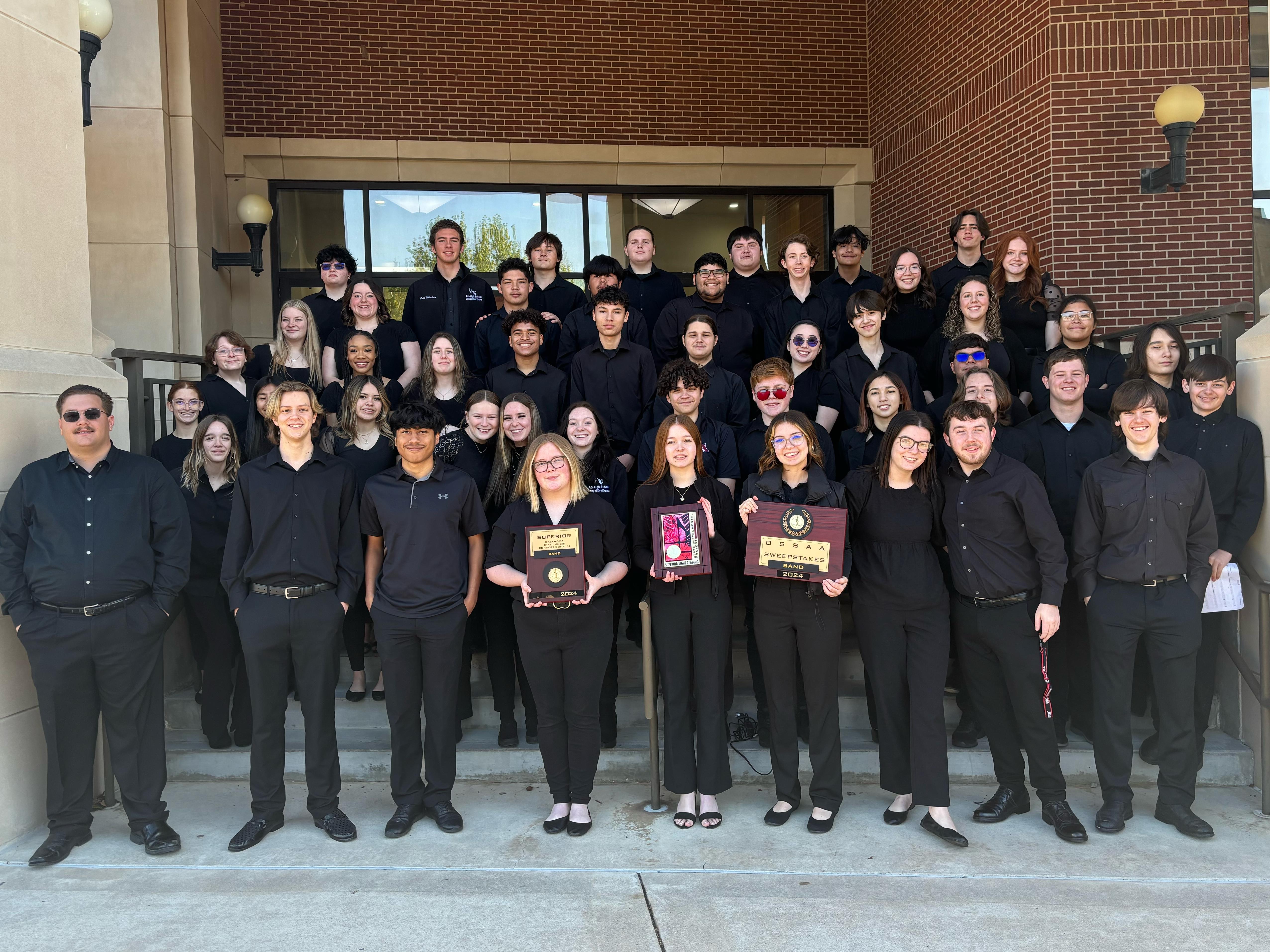 Ada High School Concert band poses for a picture holding awards. 
