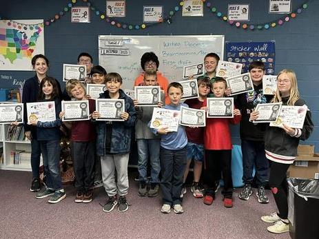 Students hold published book and certificates