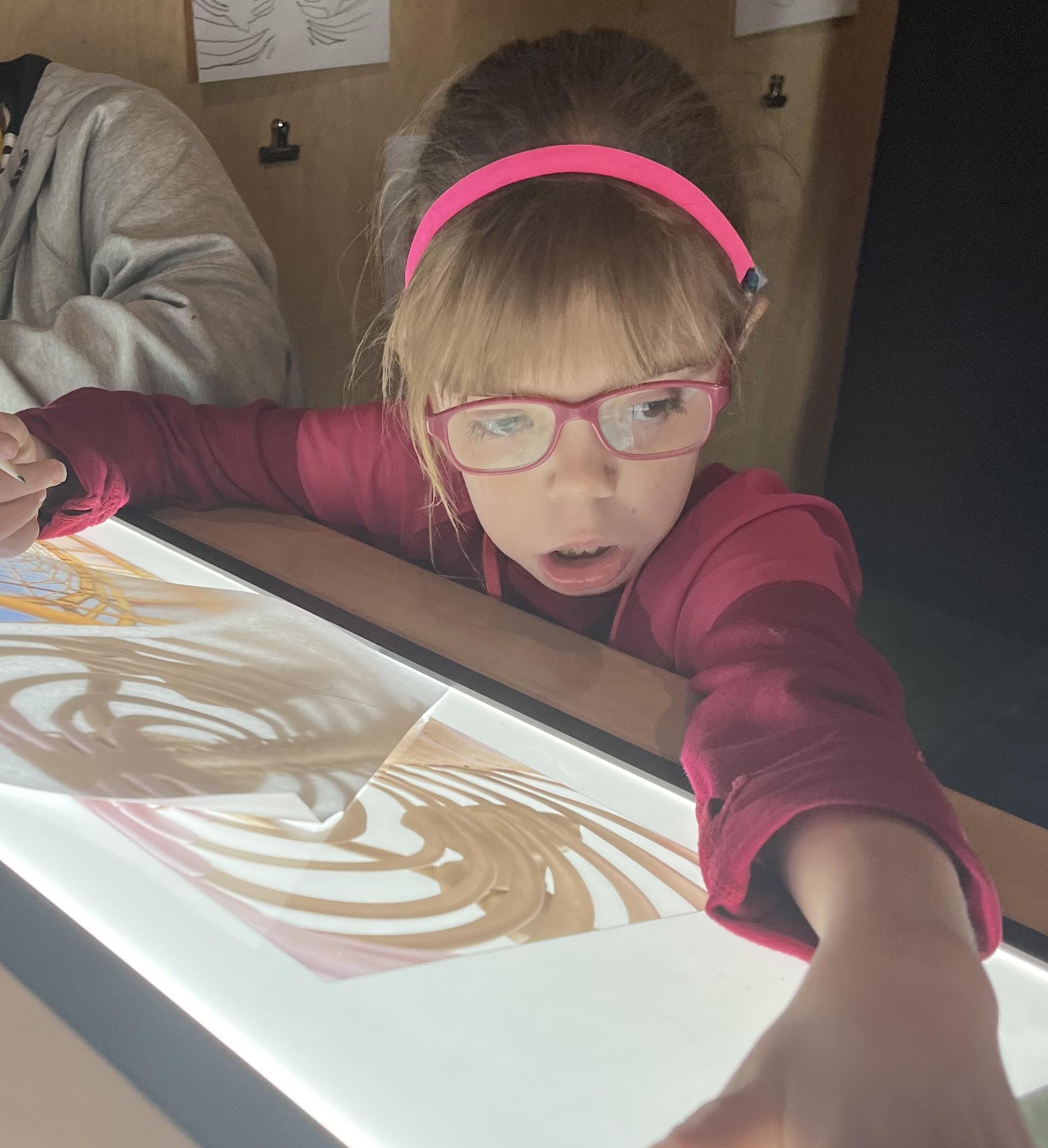 girl drawing with light behind the paper