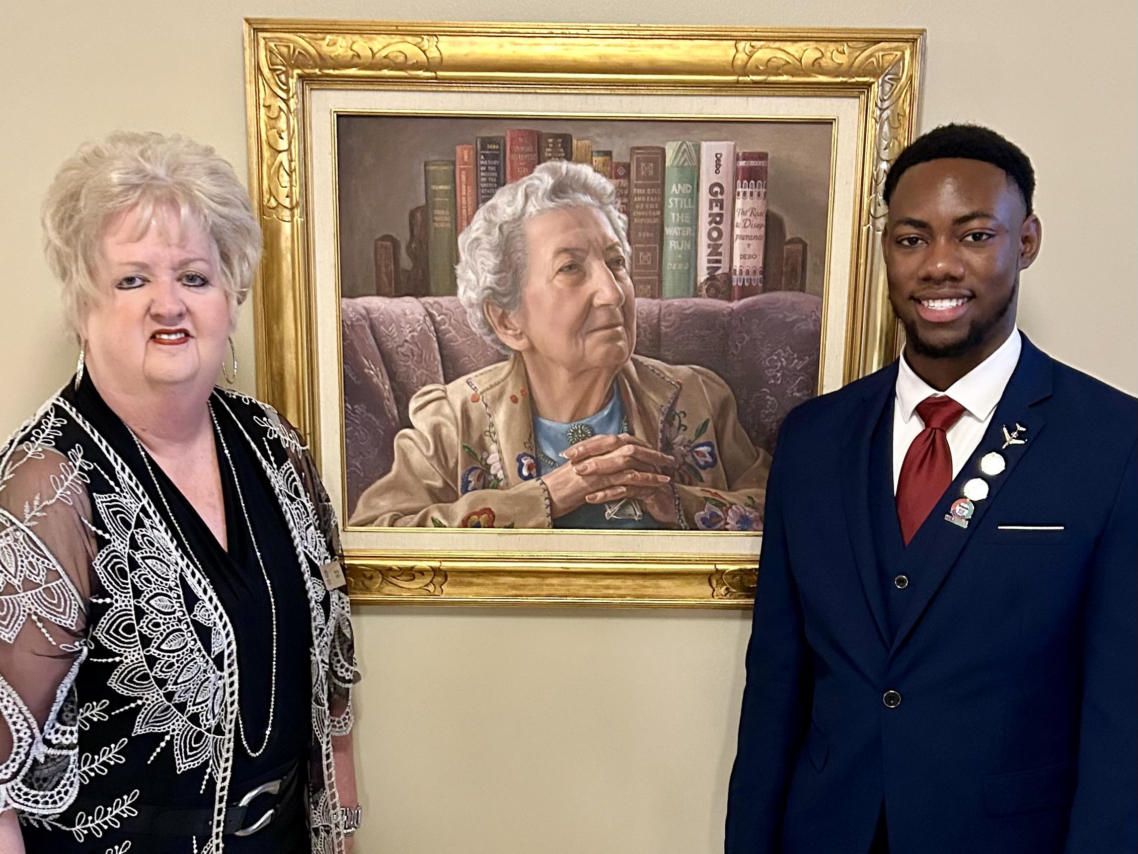 Paula Kedy and Tarique Lyons pose in front of a portrait at the Oklahoma State Capitol