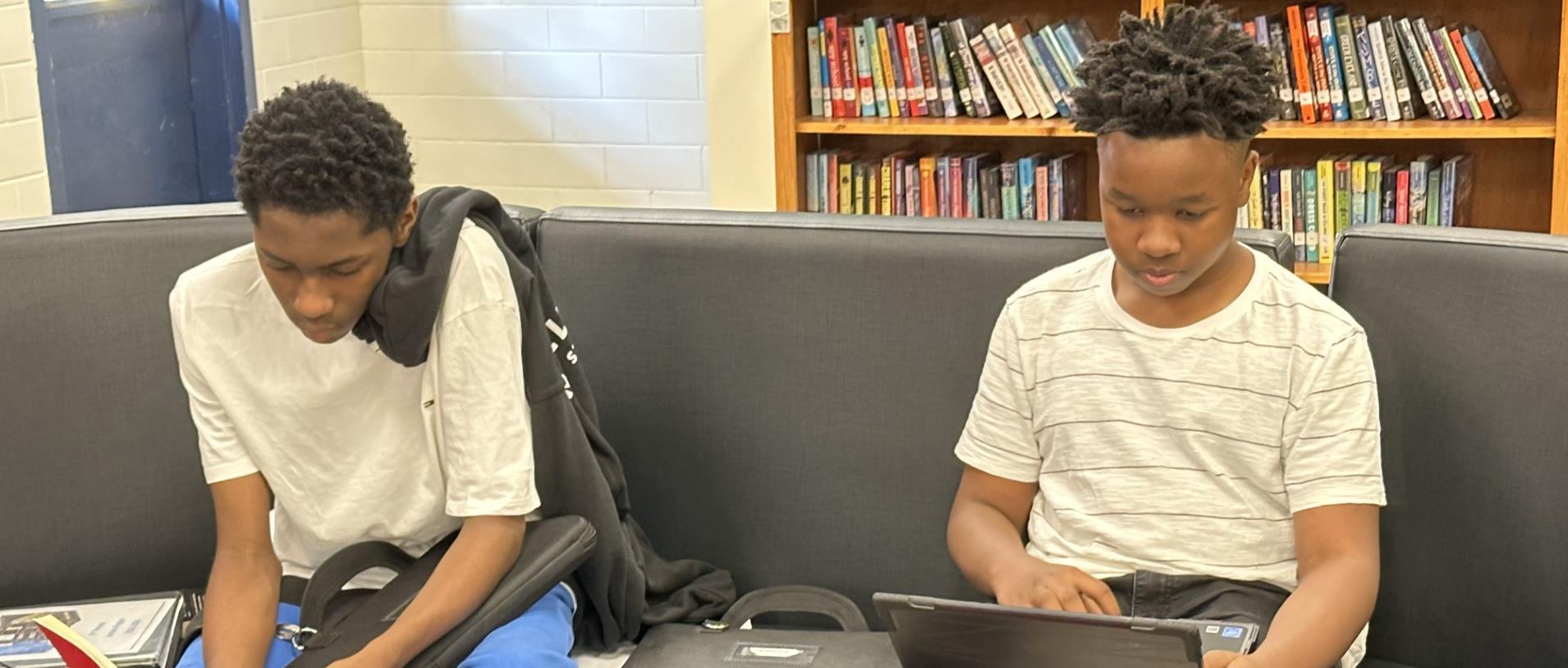 students with laptop sitting on chair 