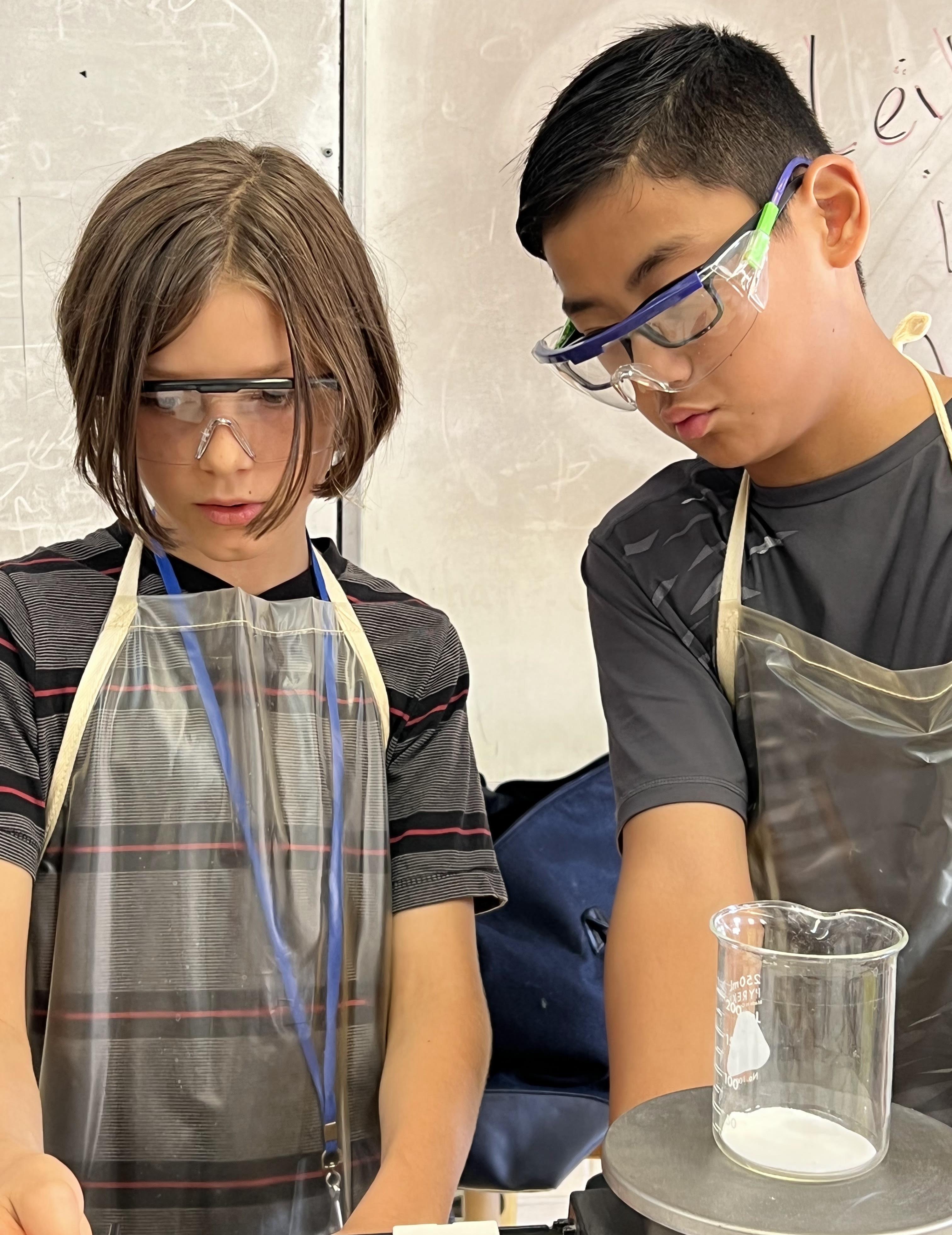 two students in science gear working on an experiment