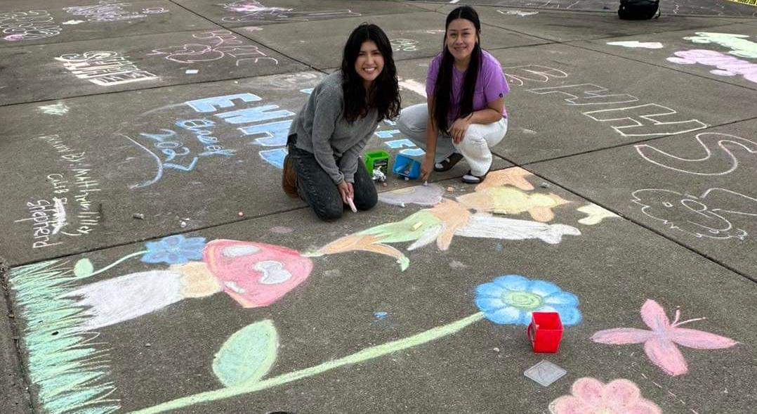 students drawing ladybugs and mushrooms on the sidewalk with chalk