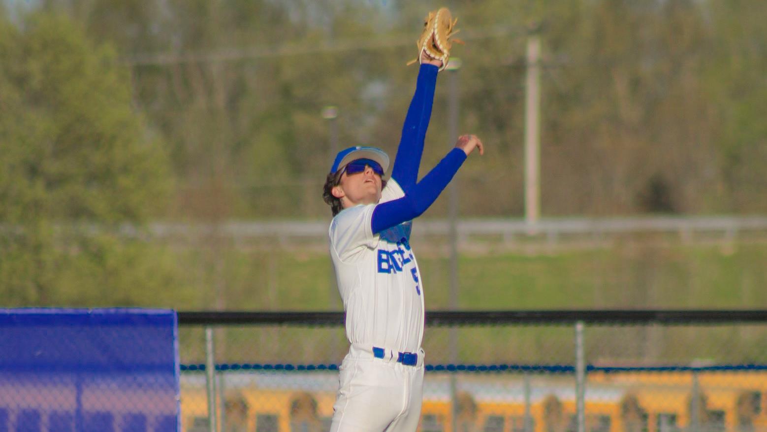 high school baseball player jumping to catch a fly ball